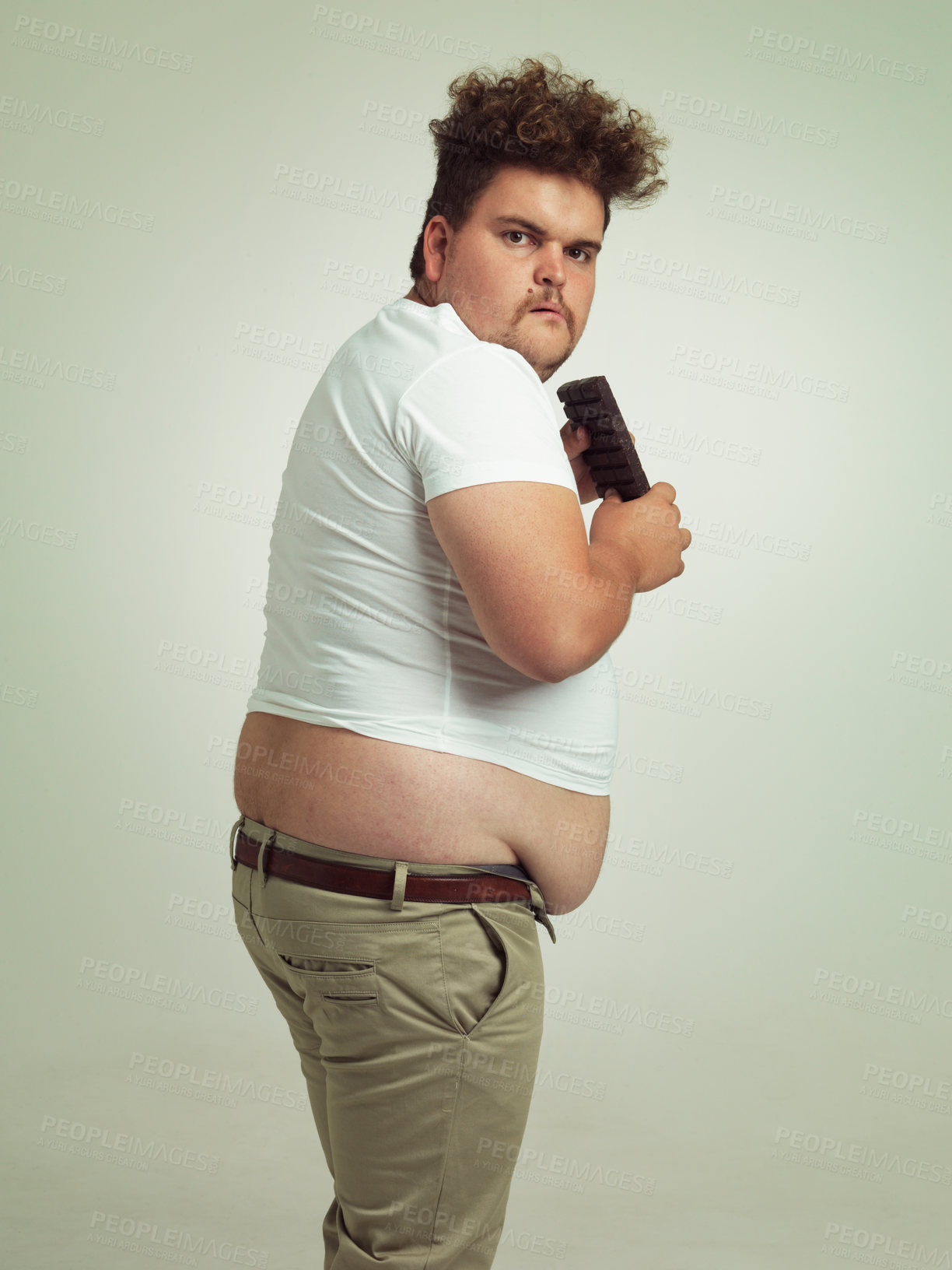 Buy stock photo Chocolate, portrait and plus size man with junk food, dessert and candy in a studio. Funny, sweet and unhealthy snack for eating with greed gesture and hungry male person with green background