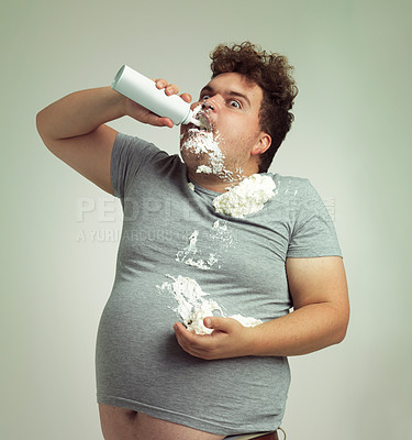 Buy stock photo Shot of an overweight man filling his mouth with whipped cream