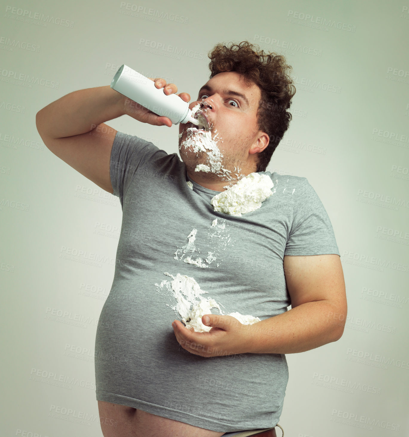 Buy stock photo Shot of an overweight man filling his mouth with whipped cream