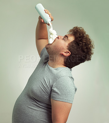 Buy stock photo Plus size, eating and man with cream in studio for unhealthy, sugar and sweet snack or dessert. Messy, greedy and hungry male person enjoying whipped dairy product for humor by gray background.