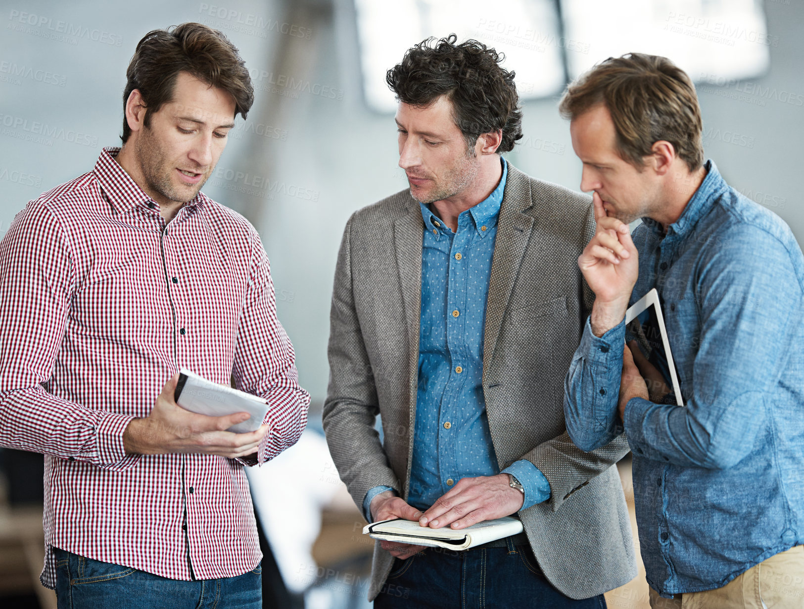 Buy stock photo Shot of a group of male coworkers taking over a digital tablet in an office