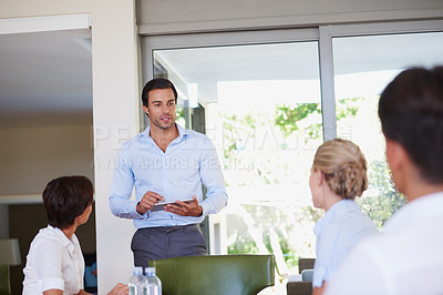 Buy stock photo Shot of a handsome businessman delivering a presentation during an office meeting