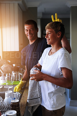 Buy stock photo Cropped shot of a father and son cleaning dishes together at home