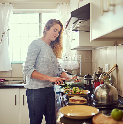 Buy stock photo Cropped shot of an attractive young woman preparing a nutritious meal at home