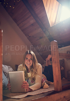 Buy stock photo Portrait of a young woman using her tablet while relaxing in her bedroom at home