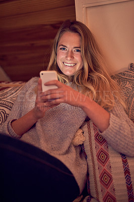 Buy stock photo Portrait of a young woman texting on her smartphone while relaxing in her bedroom at home