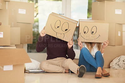 Buy stock photo Shot of a young couple on moving day wearing boxes with smiley face drawn on them on their heads