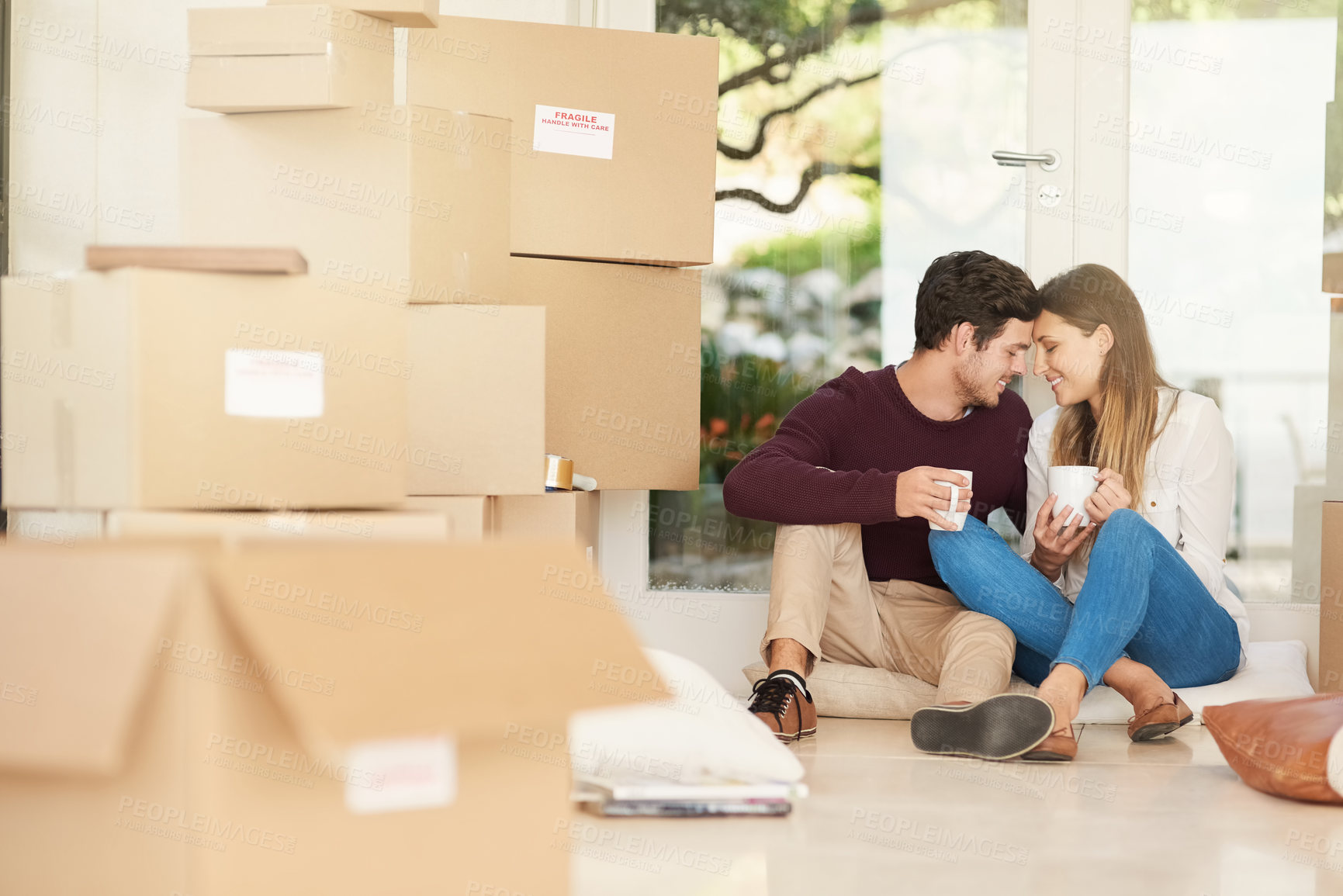 Buy stock photo Shot of an affectionate young couple taking a coffee break while moving into a new home