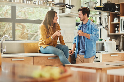 Buy stock photo Shot of an affectionate young couple conversing in their kitchen