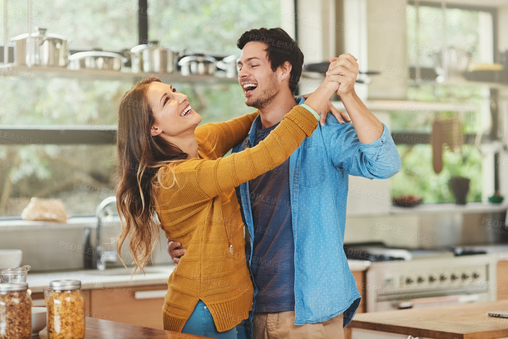 Buy stock photo Shot of an affectionate young couple dancing in their kitchen