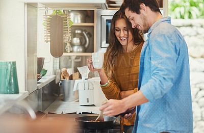 Buy stock photo Shot of an attractive young woman watching her boyfriend cook in their kitchen