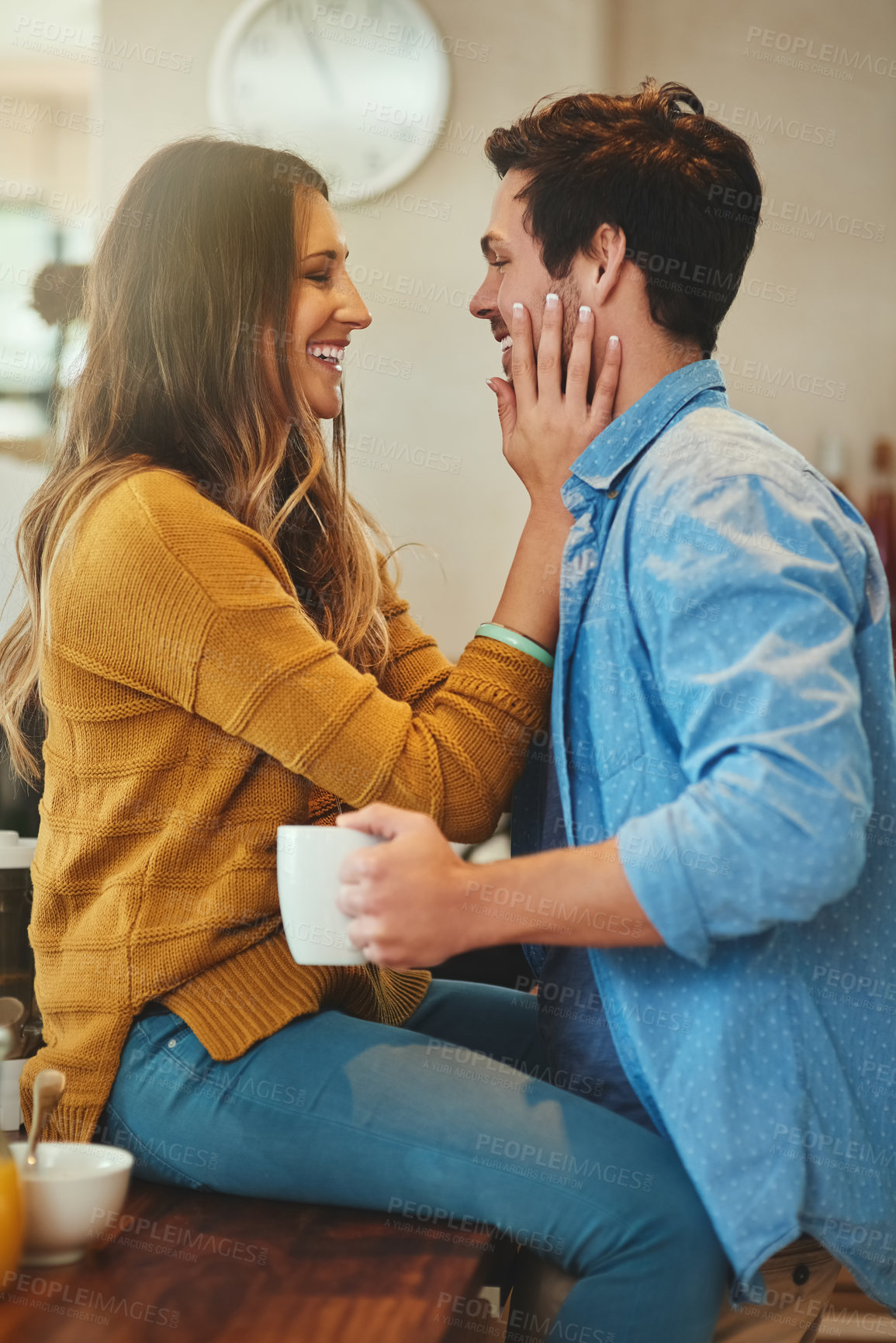 Buy stock photo Couple, love and happy in home kitchen,  trust and hands on face with people together for relationship bonding. Beverage, commitment and caring partner or smile, apartment and sitting on dining table