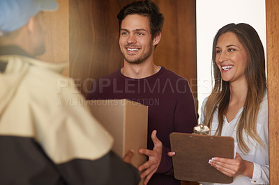 Buy stock photo Shot of a courier delivering a package to a smiling young couple at home