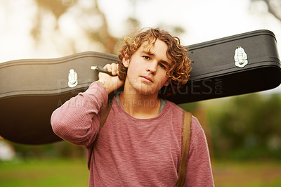 Buy stock photo Portrait of a young man standing outside carrying a guitar case over his shoulder