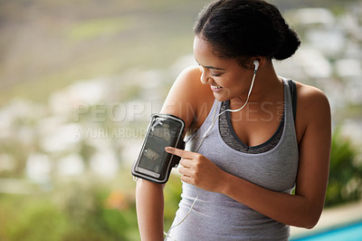 Buy stock photo Cropped shot of a sporty young woman checking her playlist before a run