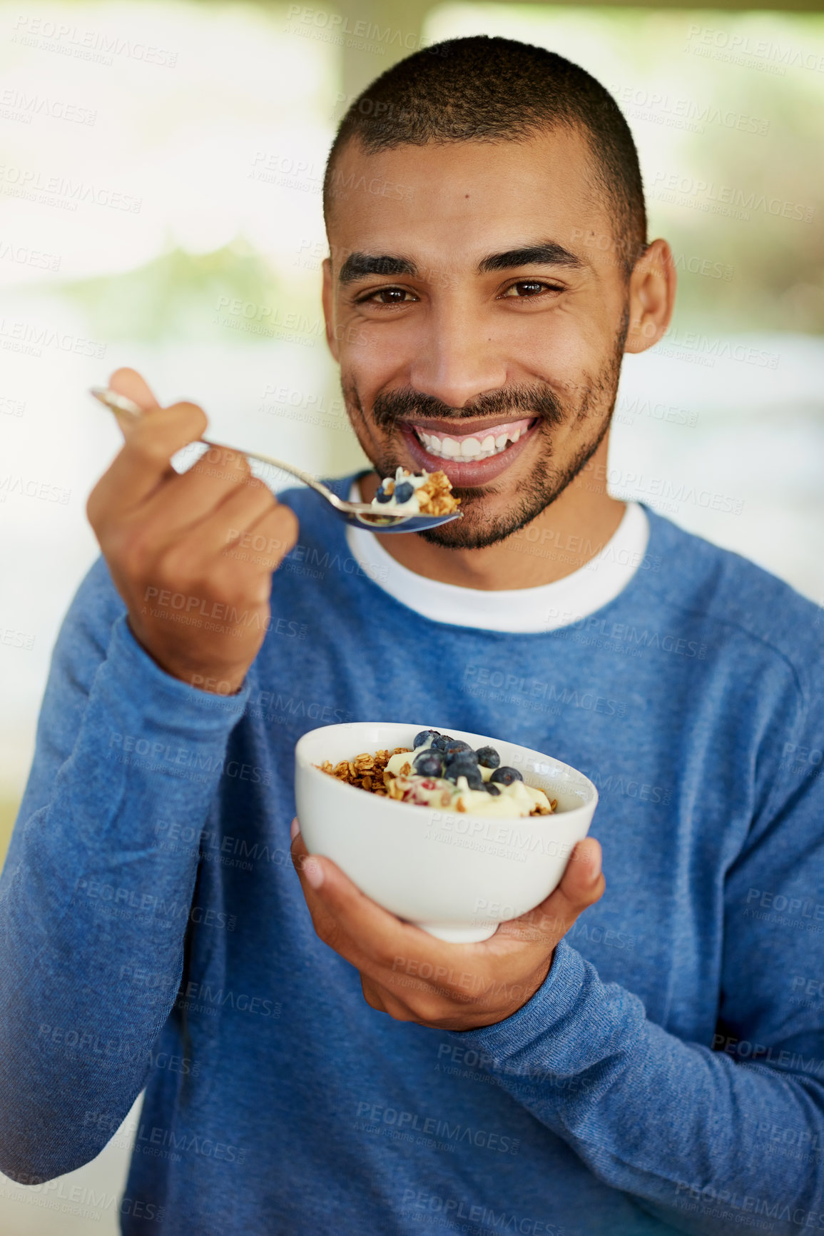 Buy stock photo Portrait of a happy young man enjoying a bowl of muesli at home