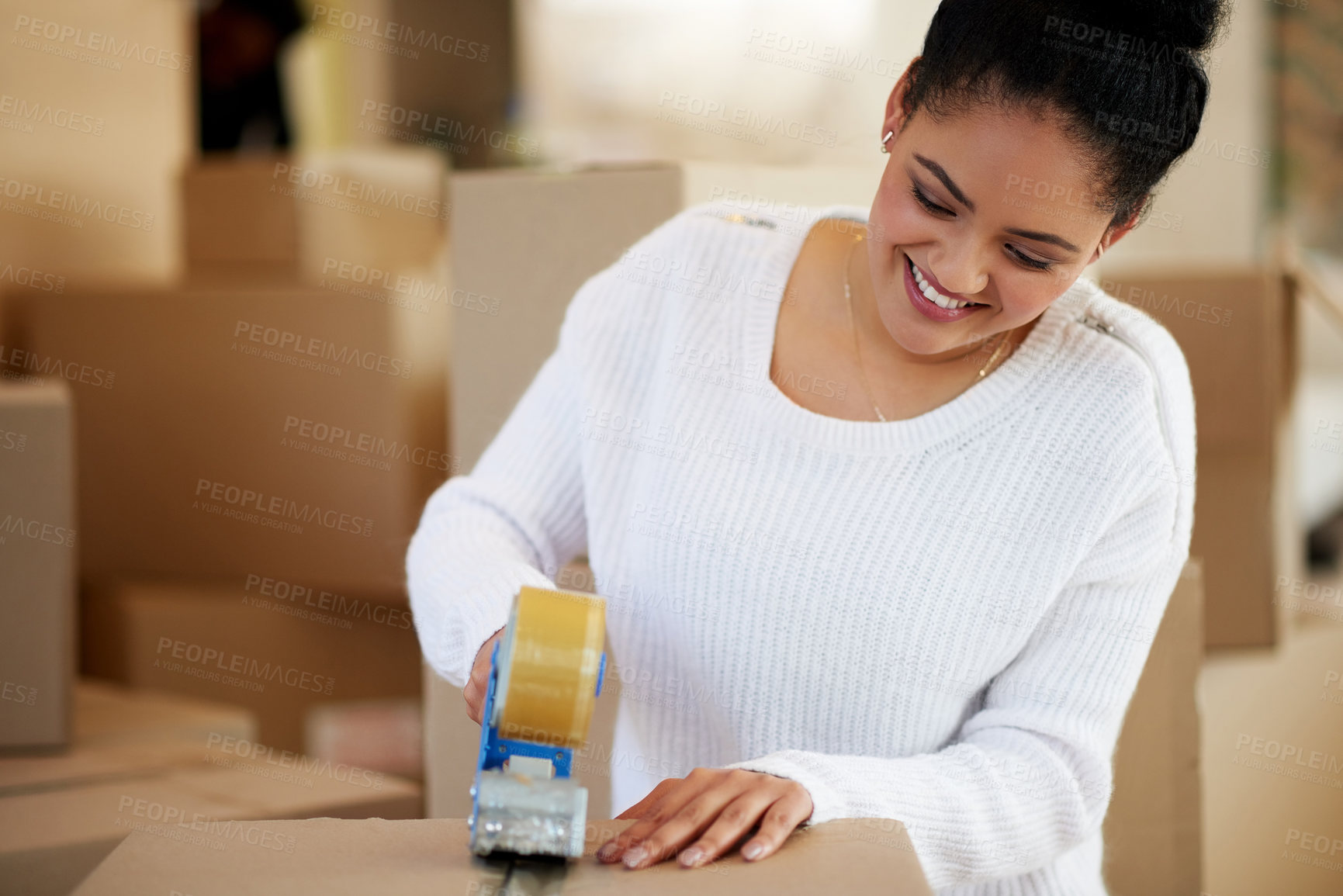 Buy stock photo Shot of a happy young woman packing boxes while moving house