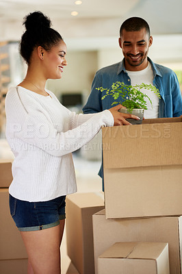 Buy stock photo Shot of a happy young couple unpacking boxes in their new home together