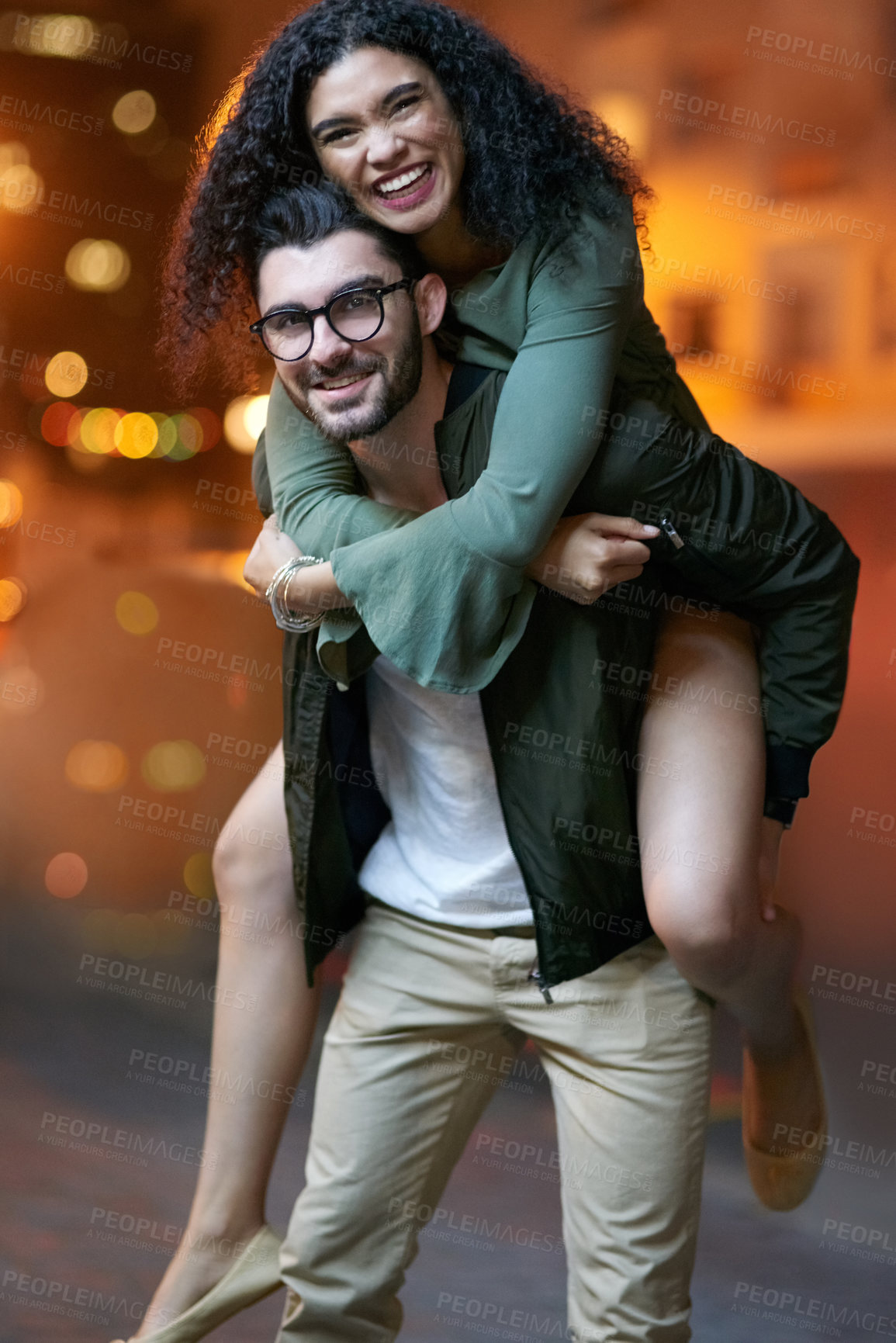 Buy stock photo Portrait of a handsome young man piggybacking his girlfriend outdoors at night