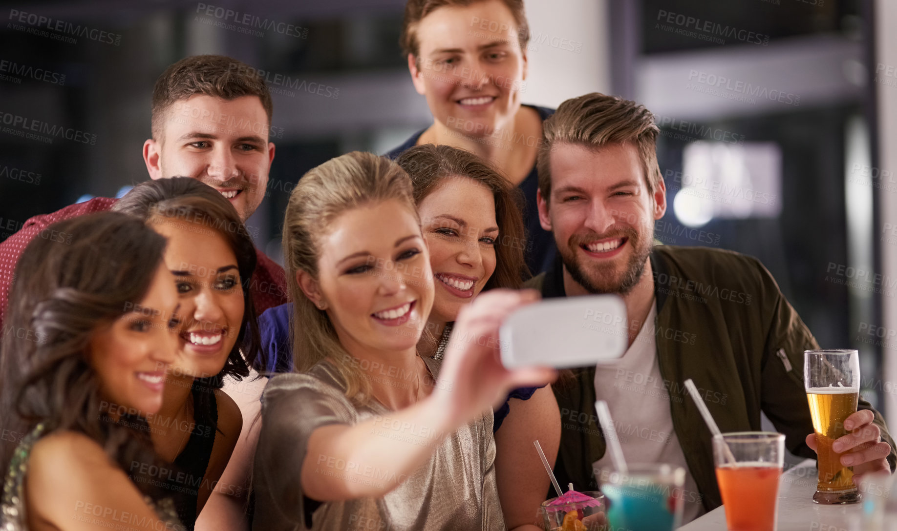 Buy stock photo Shot of a happy group of friends taking a selfie while having drinks at a bar together