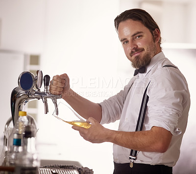 Buy stock photo Portrait of a handsome young barman poring a beer in a bar