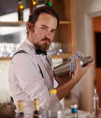 Buy stock photo Portrait of a handsome young barman mixing a cocktail in a bar