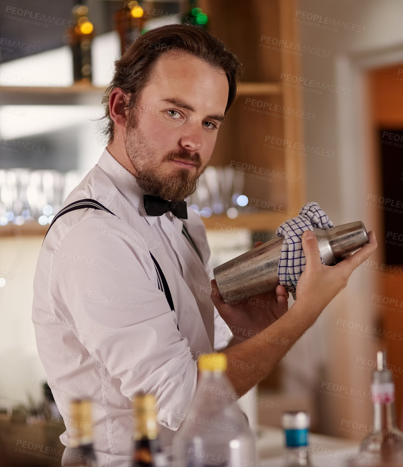 Buy stock photo Portrait of a handsome young barman mixing a cocktail in a bar