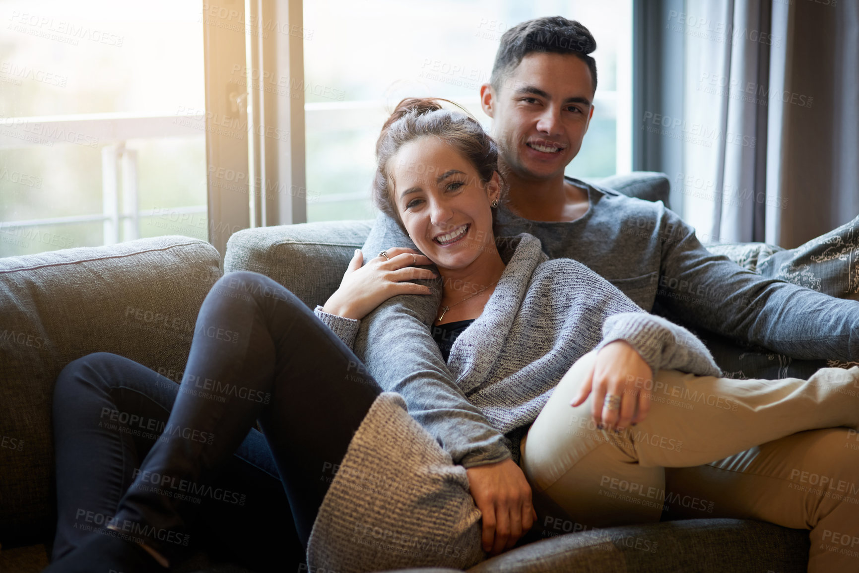 Buy stock photo Portrait of an affectionate young couple relaxing on the sofa at home
