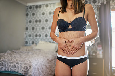 Buy stock photo Shot of an attractive young woman in underwear making a heart shape on her stomich with her hands