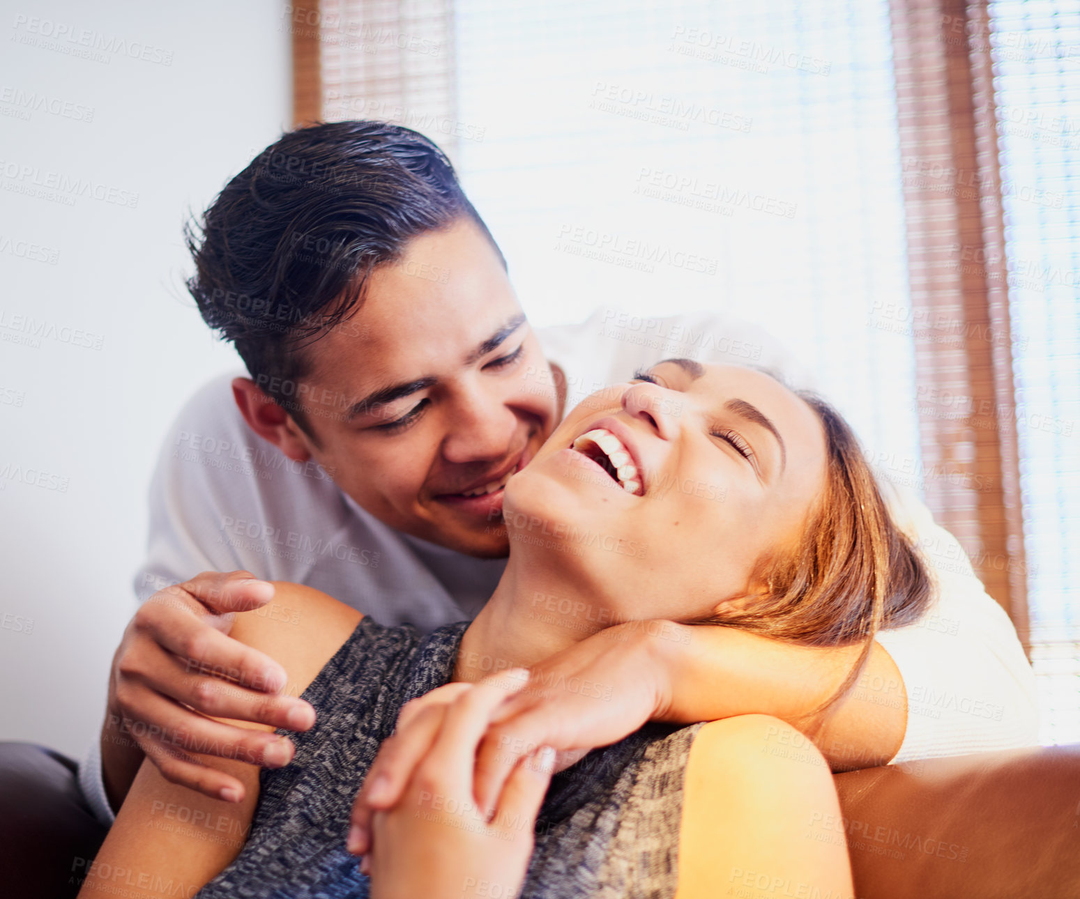 Buy stock photo Shot of a laughing young couple sharing a moment together at home