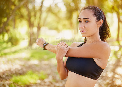 Buy stock photo Shot of a sporty young woman stretching before her run