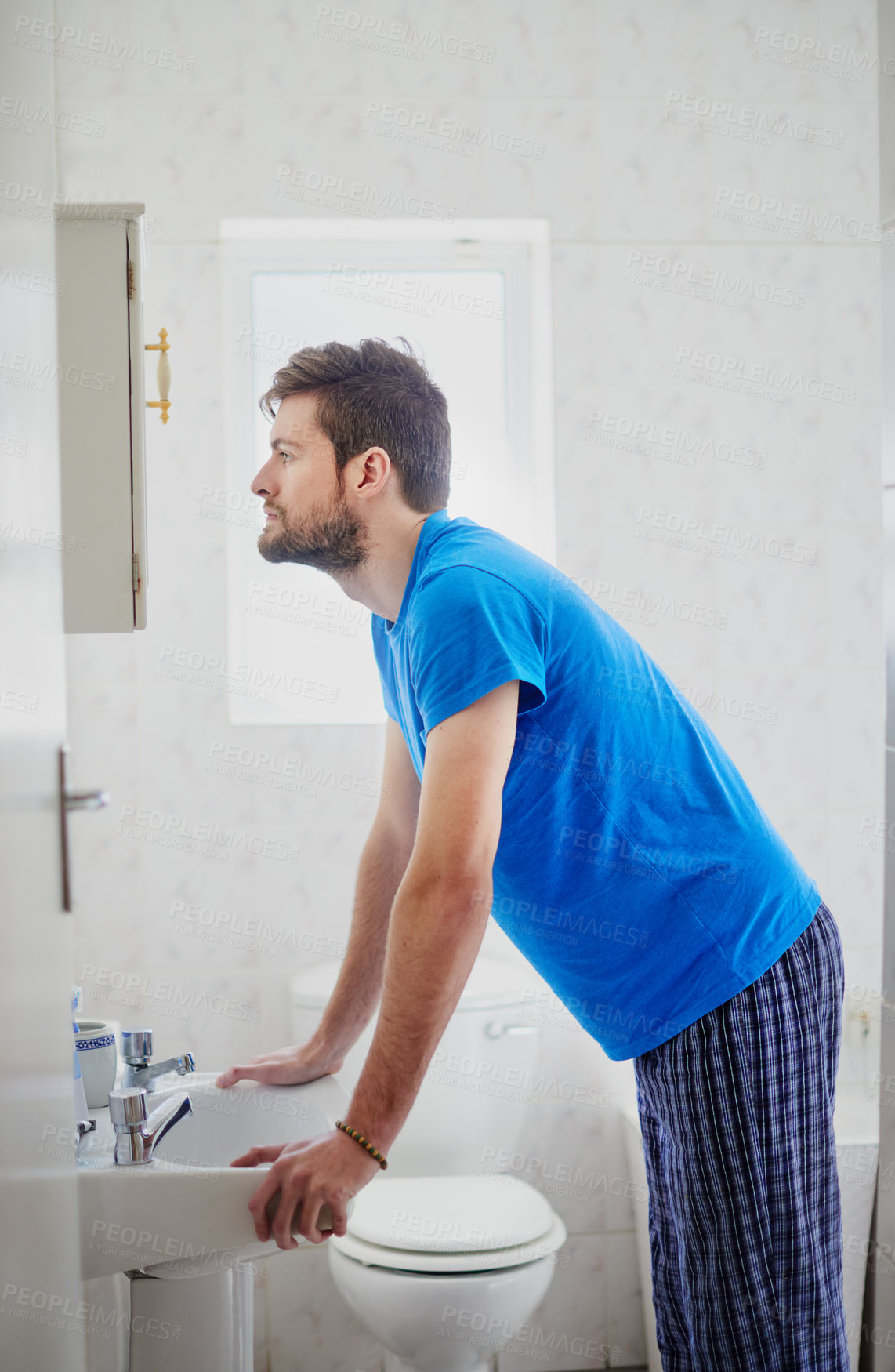 Buy stock photo Cropped shot of a young man standing in front of a bathroom mirror