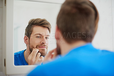 Buy stock photo Cropped shot of a young man squeezing a pimple in front of a bathroom mirror