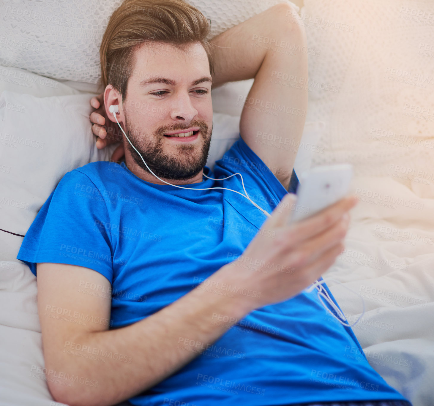 Buy stock photo Cropped shot of a handsome young man listening to music while lying on his bed at home