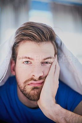 Buy stock photo Portrait of a handsome young man looking bored while lying in bed