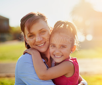 Buy stock photo Portrait of a smiling mother hugging her little daughter while enjoying a day together in the park