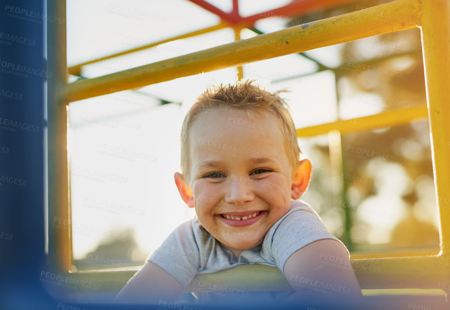 Buy stock photo Portrait of a smiling little boy playing on a jungle gym in the park
