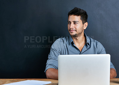 Buy stock photo Cropped shot of a handsome young businessman working on his laptop against a dark background