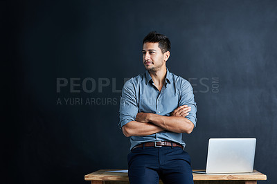 Buy stock photo Cropped shot of a handsome young businessman standing in front of a desk against a dark background