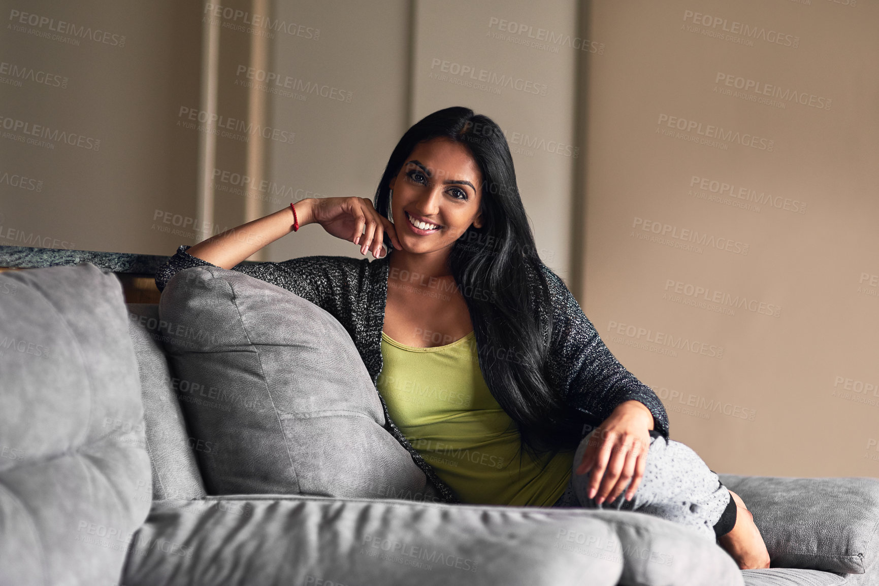 Buy stock photo Portrait of an attractive young woman sitting on her sofa at home