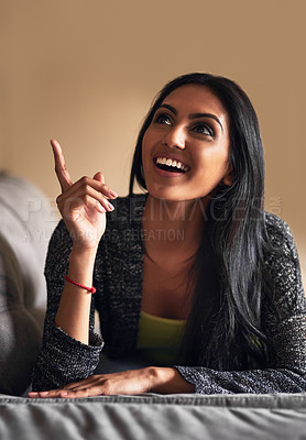 Buy stock photo Shot of an attractive young woman looking inspired while lying on her sofa at home