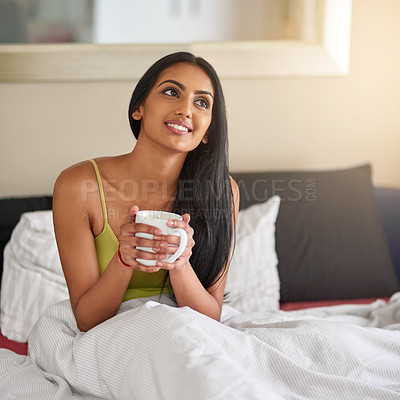 Buy stock photo Shot of a thoughtful young woman having her morning coffee in bed
