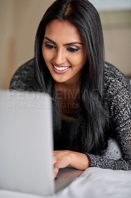 Buy stock photo Shot of a young woman relaxing on the bed and using a laptop