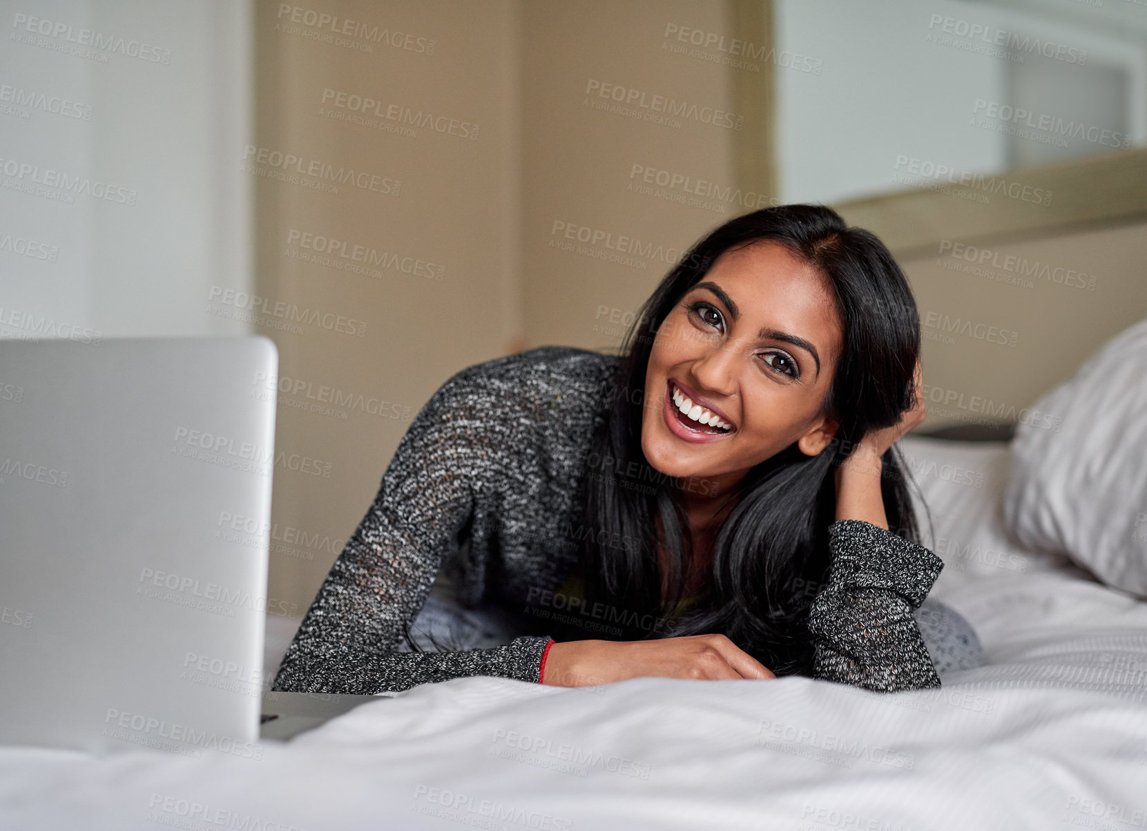 Buy stock photo Portrait of a young woman relaxing on the bed and using a laptop