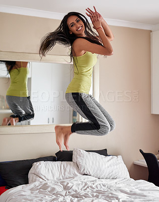 Buy stock photo Portrait of an energetic young woman jumping on the bed at home