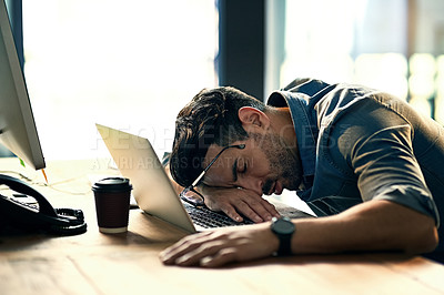 Buy stock photo Shot of an exhausted young businessman sleeping at his desk during a late night at work