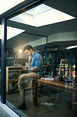 Buy stock photo Shot of a young businessman using a digital tablet during a late night at work