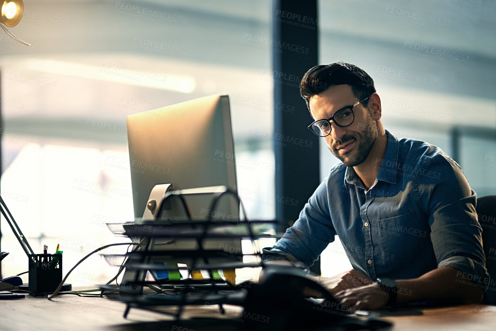 Buy stock photo Portrait of a young businessman using a computer during a late night at work