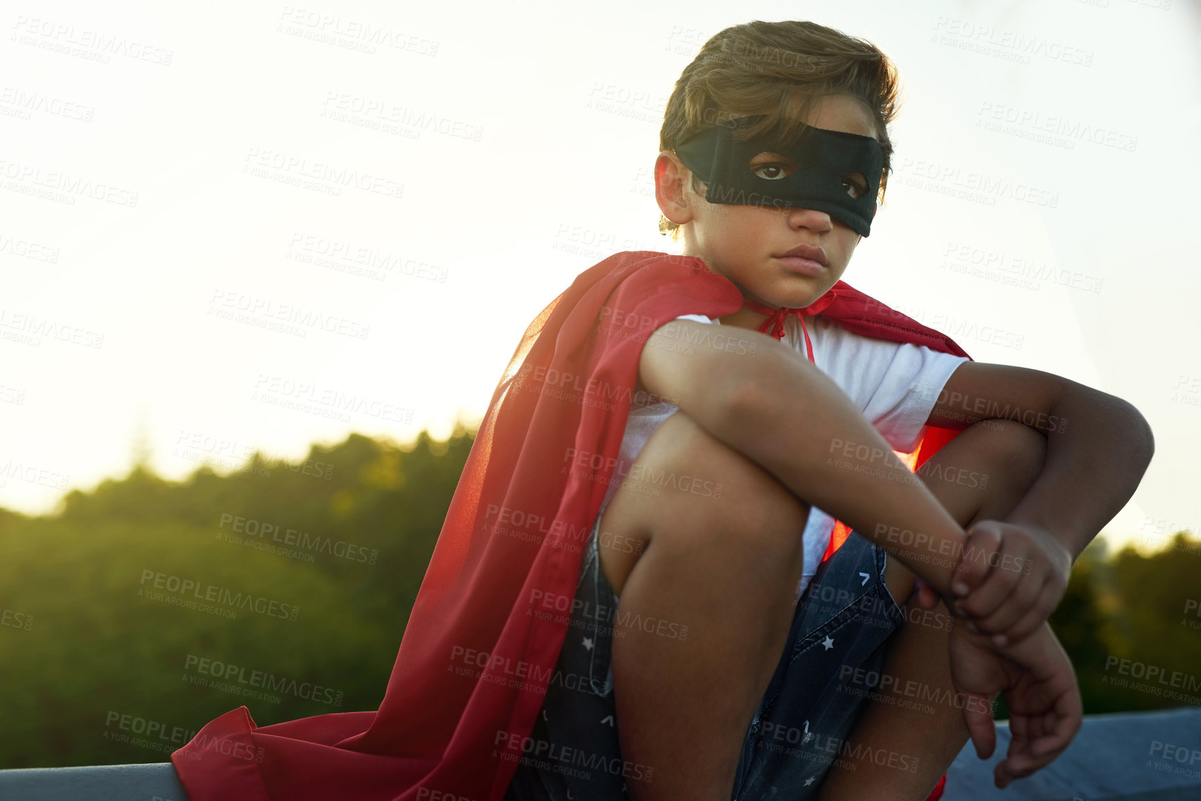 Buy stock photo Shot of a young boy in a cape and mask playing superhero outside