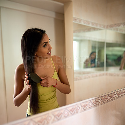 Buy stock photo Cropped shot of a young woman brushing her hair in the bathroom